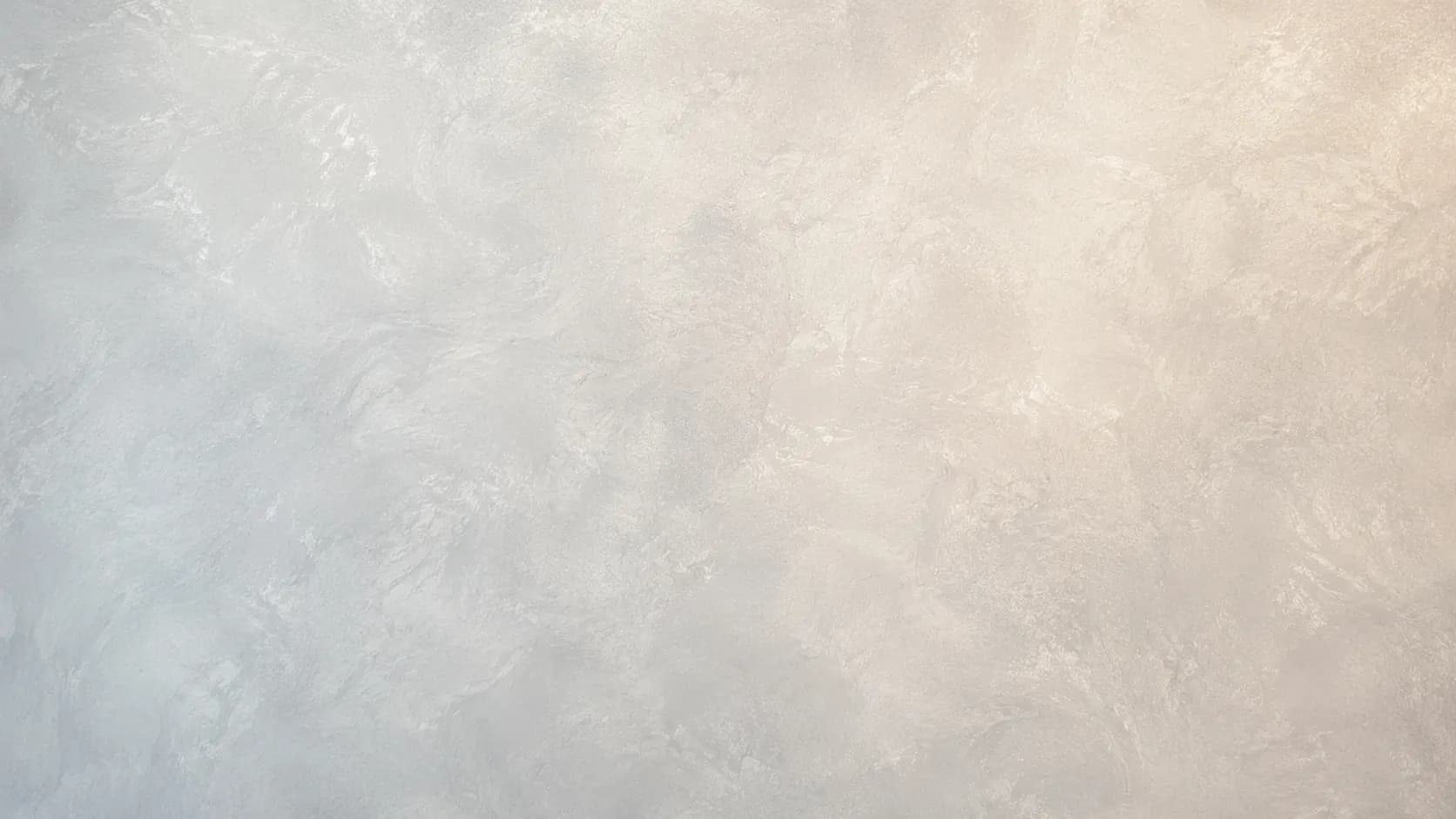 Polished decorative plaster wall blending soft gray into warm cream, with cloud-like movement and a gentle sheen.