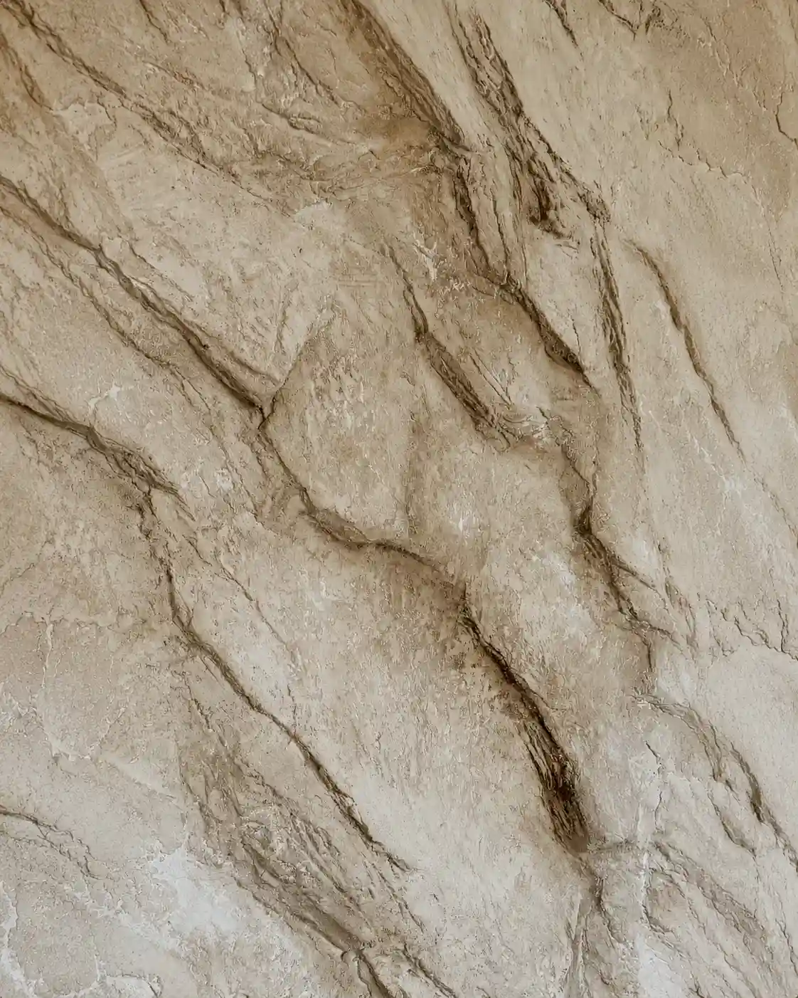 Close-up of a hand-sculpted stone-effect plaster surface, showing deep contoured relief and a rugged, rock-like texture.