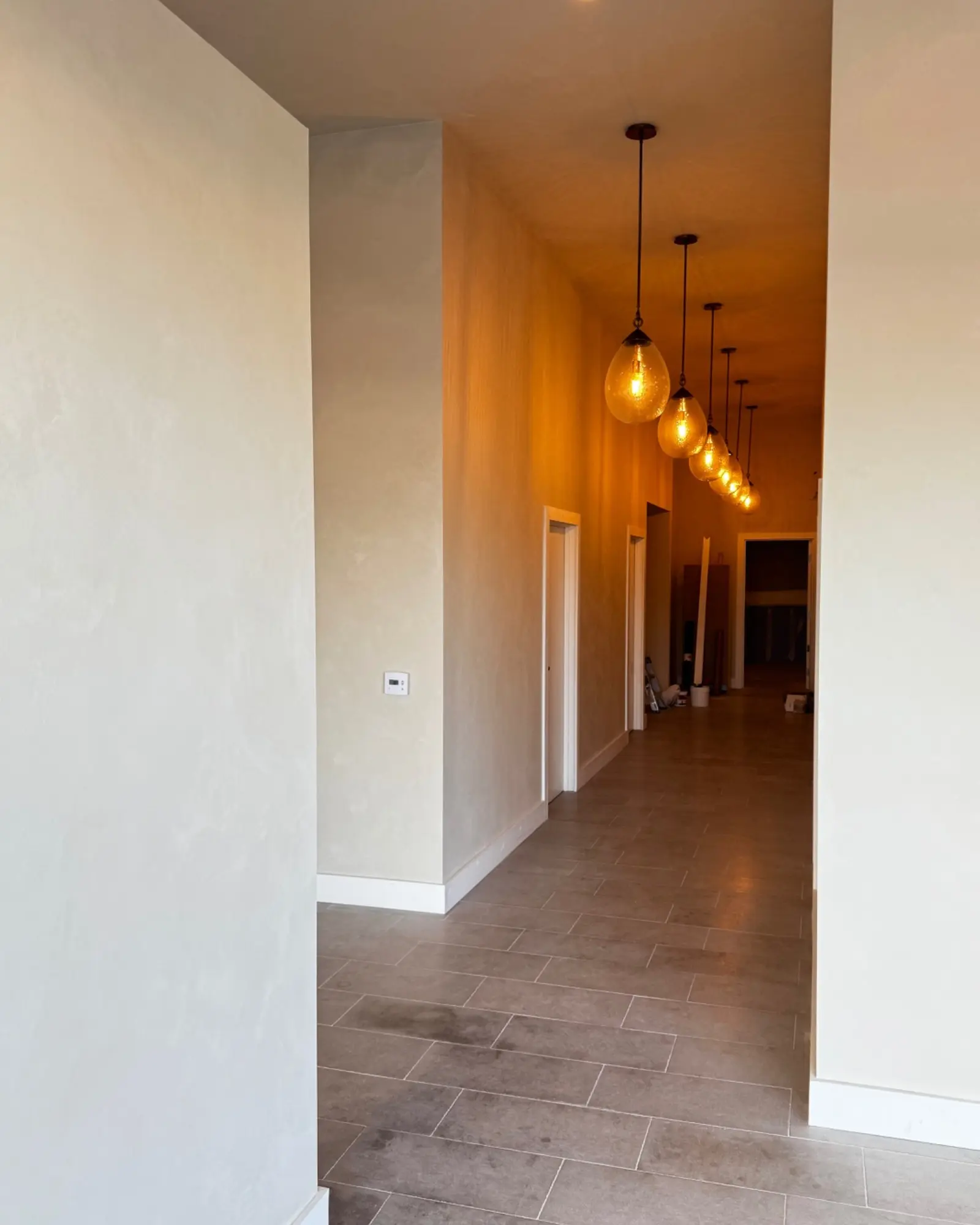 The same lime wash corridor in a Costa Mesa med spa, lit by a row of pendant lights.