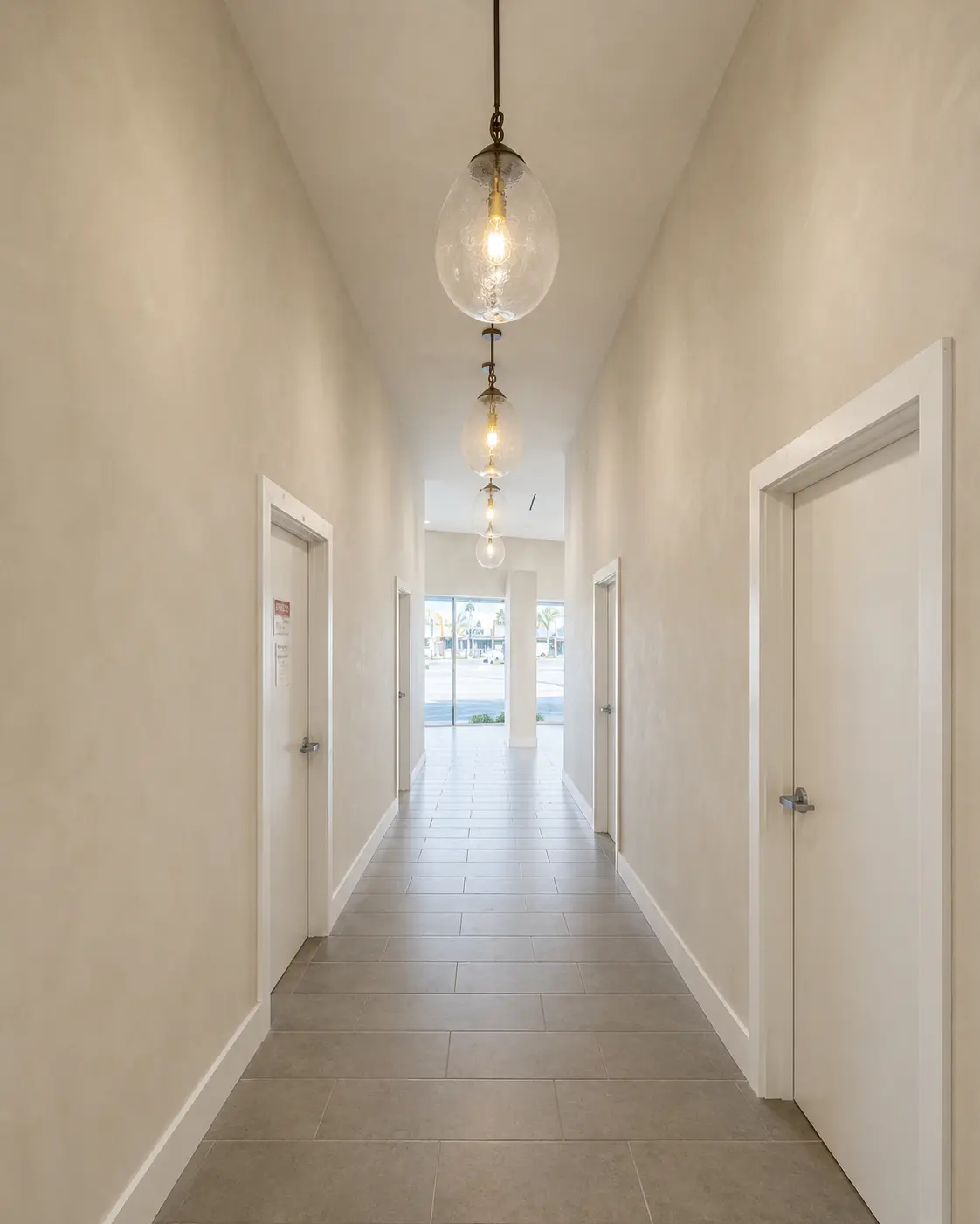 Lime wash walls in a corridor with pendant lighting.