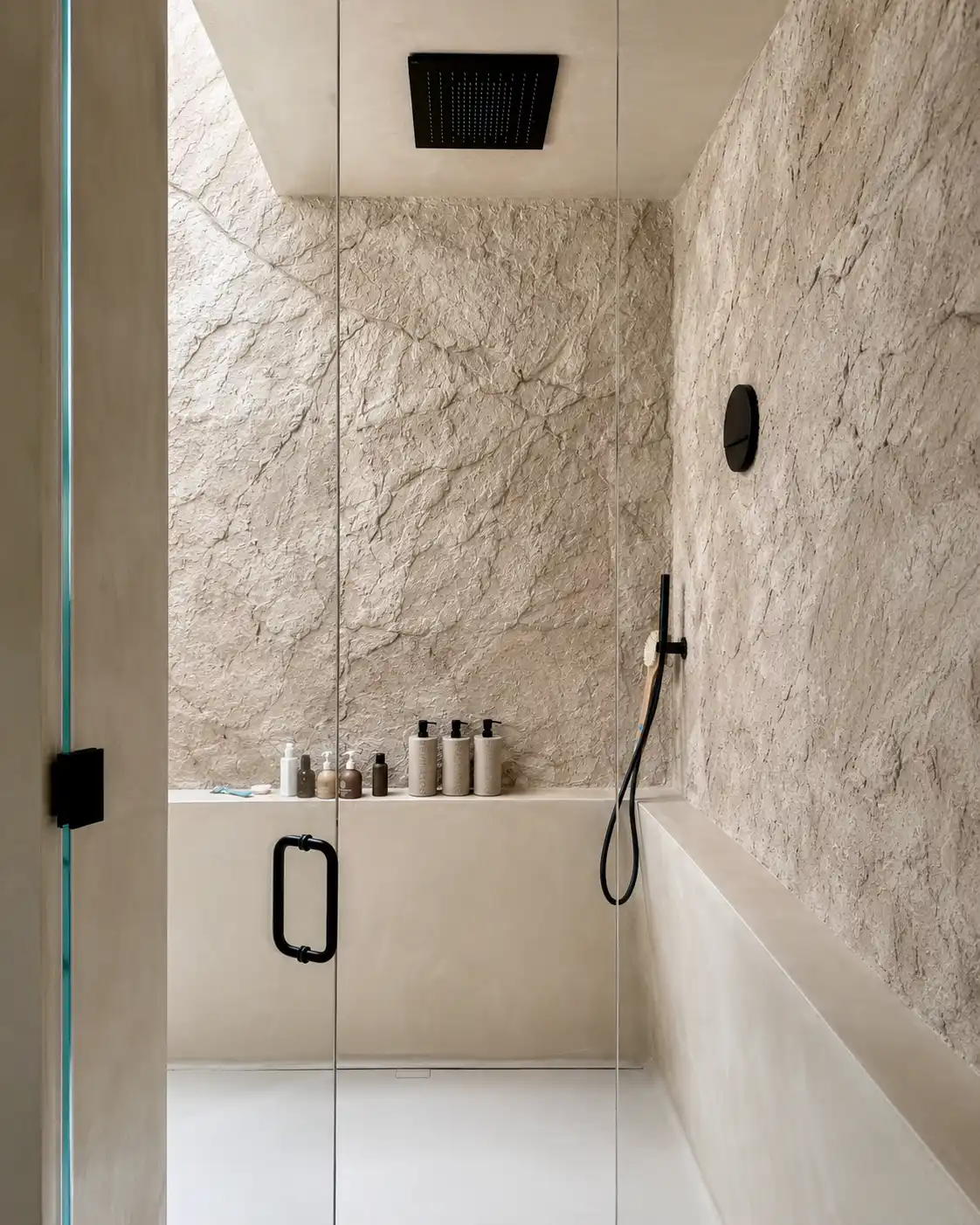 Stone-effect plaster walls in a textured shower and bath with a natural rock-like finish.