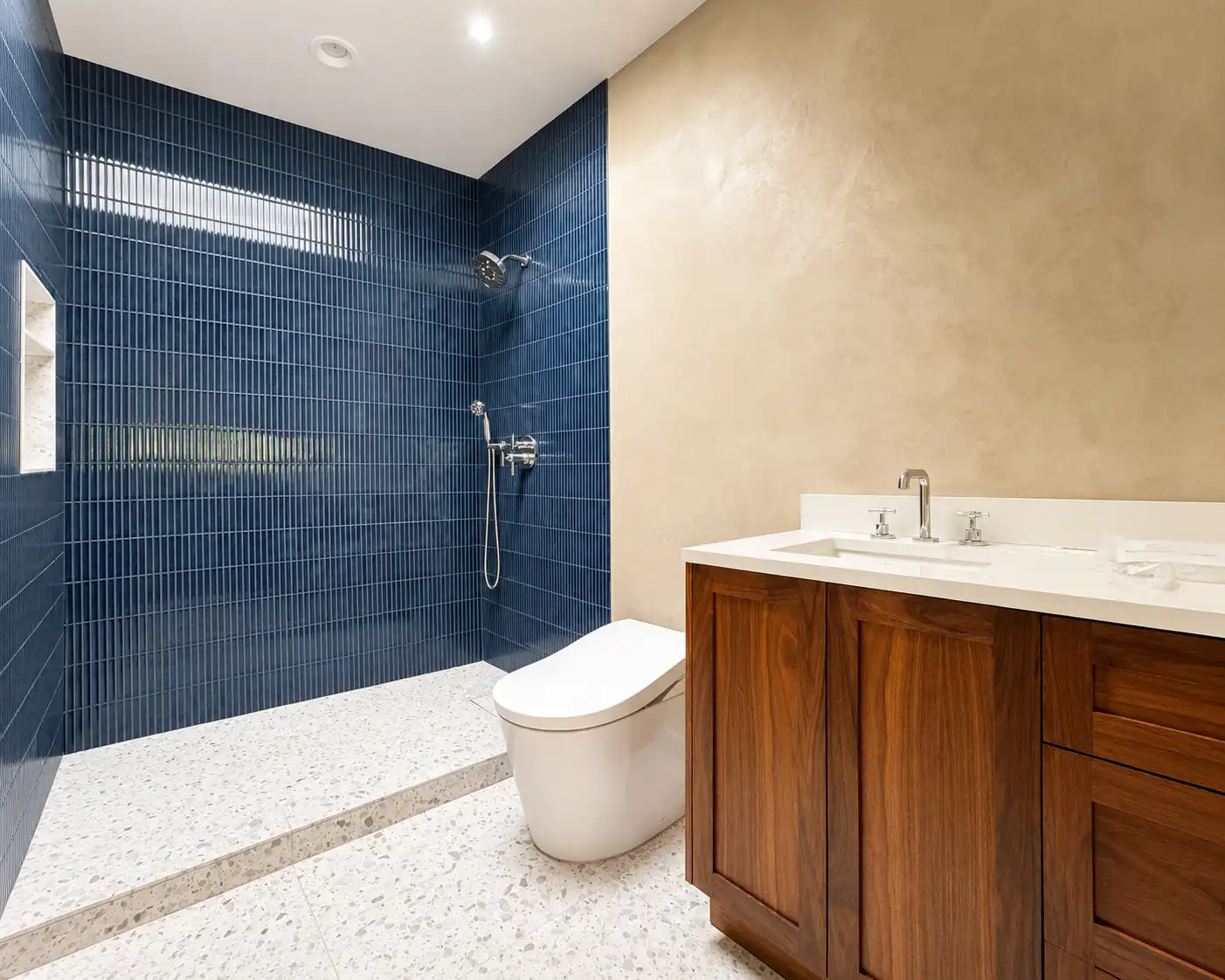 A finished Venetian Marmorino bathroom wall beside a navy fluted-tile shower, in a Santa Ana project.