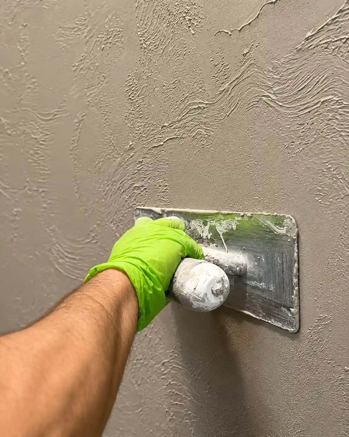 A specialist applying Marmorino plaster with a steel trowel, drawing the soft textured movement by hand.