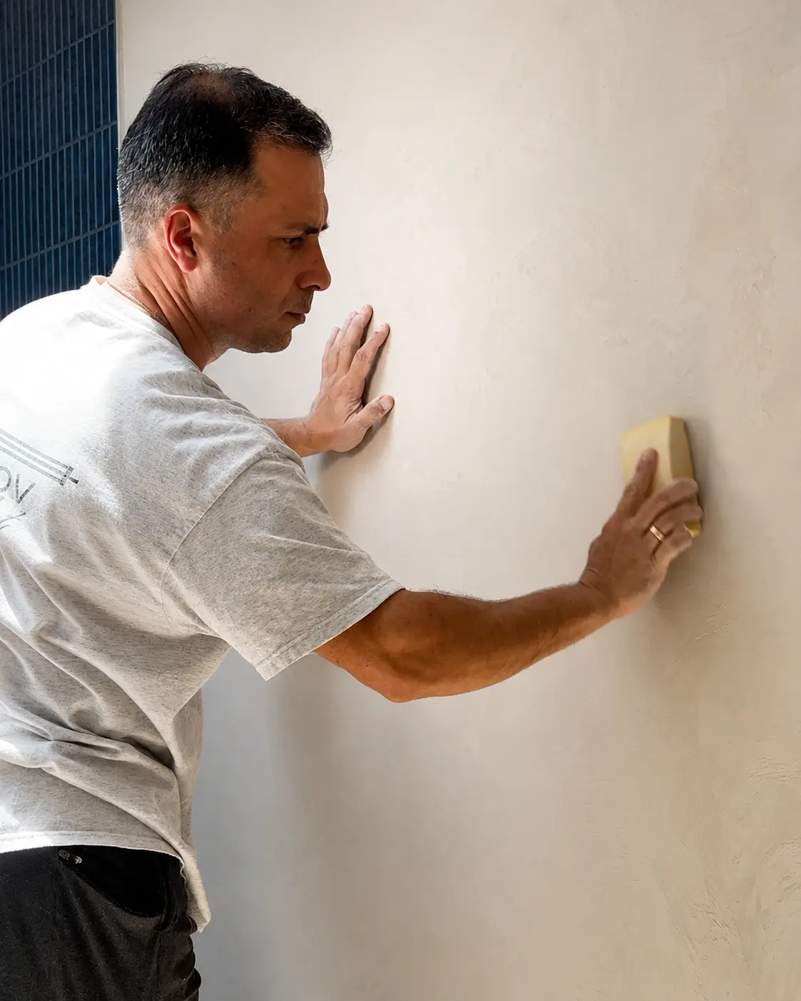 An SBK specialist hand-finishing the Marmorino wall with a sponge float to bring up its soft, even sheen.