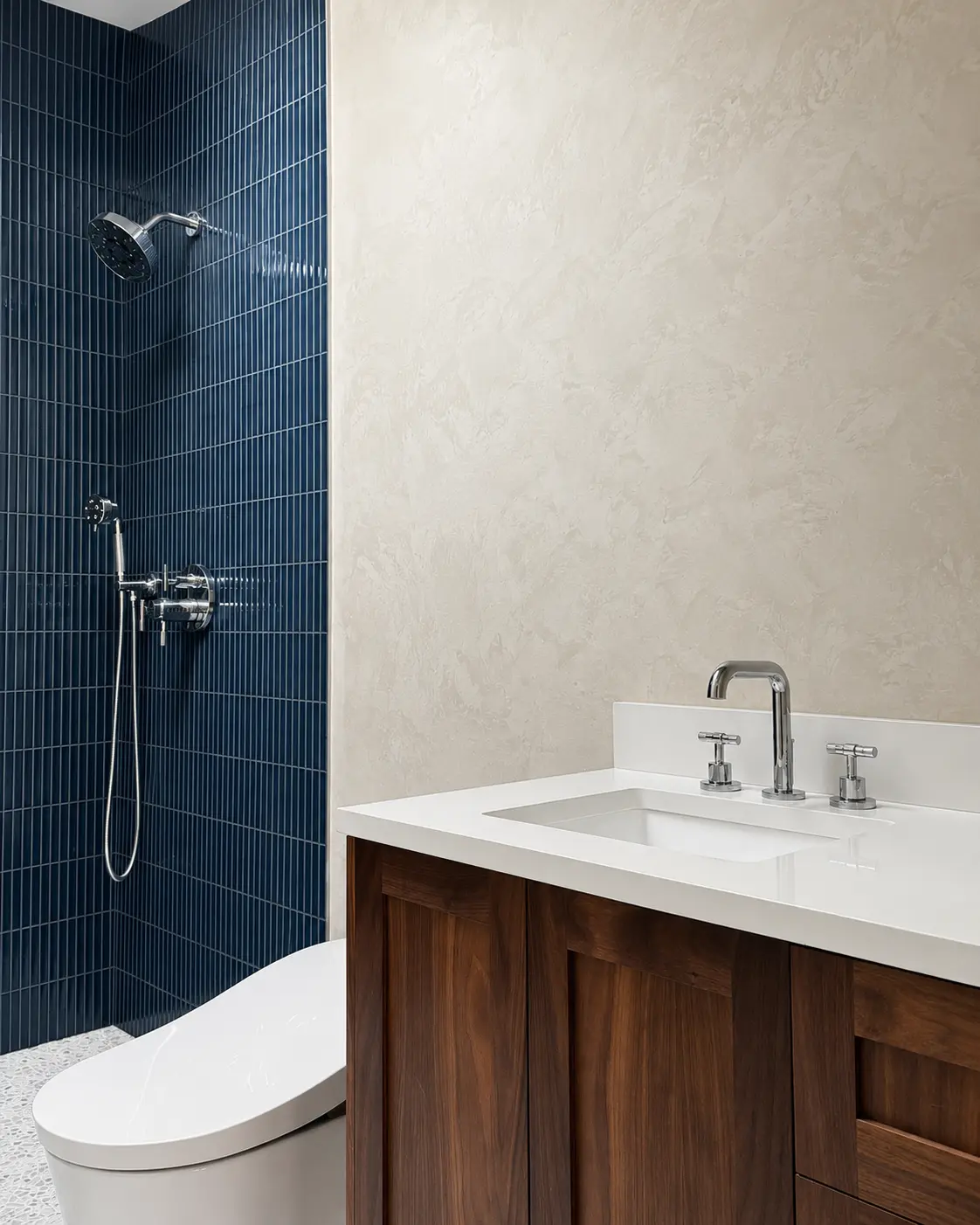 The finished bathroom with a light gray Marmorino wall, navy fluted-tile shower and walnut vanity, in a Santa Ana project.