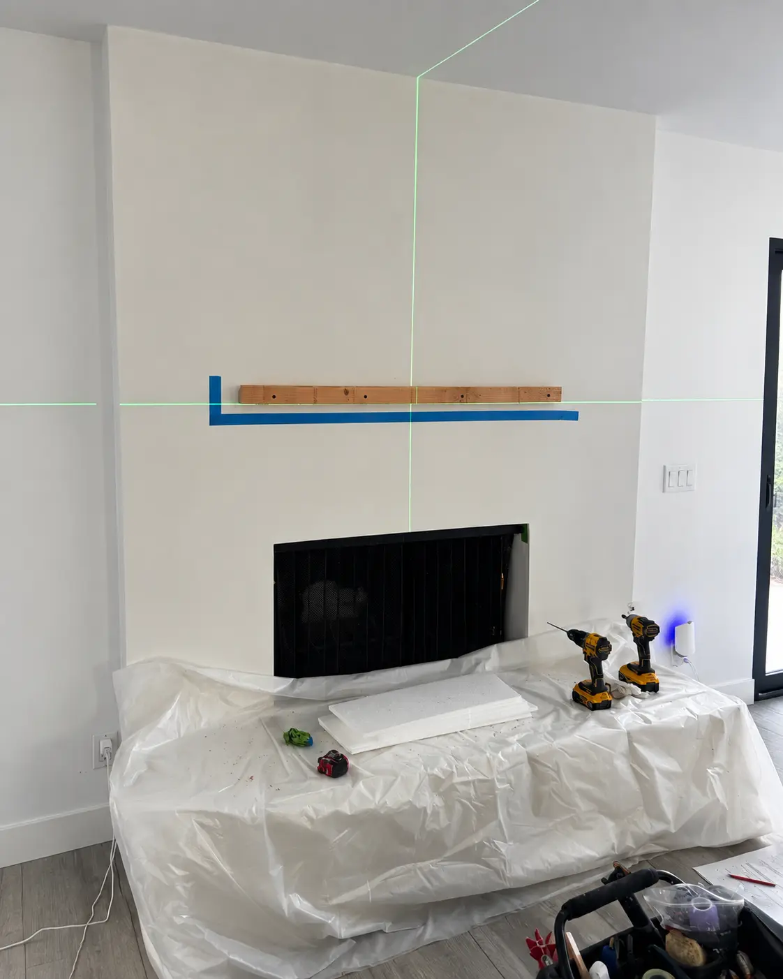 Laser layout marking the floating wood mantel position before mounting.