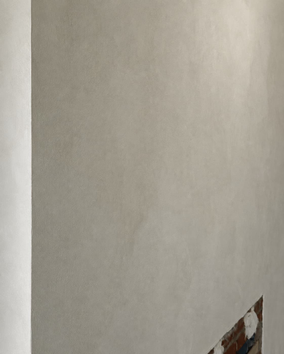 Close detail of a hand-applied lime wash surface in a light warm coffee tone.