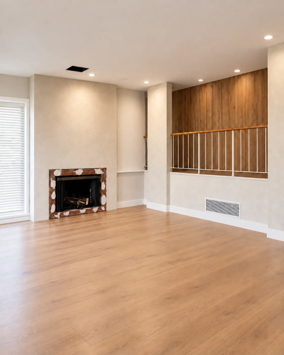 Lime wash living room in Tustin with a plaster fireplace wall and a wood-slat stair panel, warm oak floor and natural light.