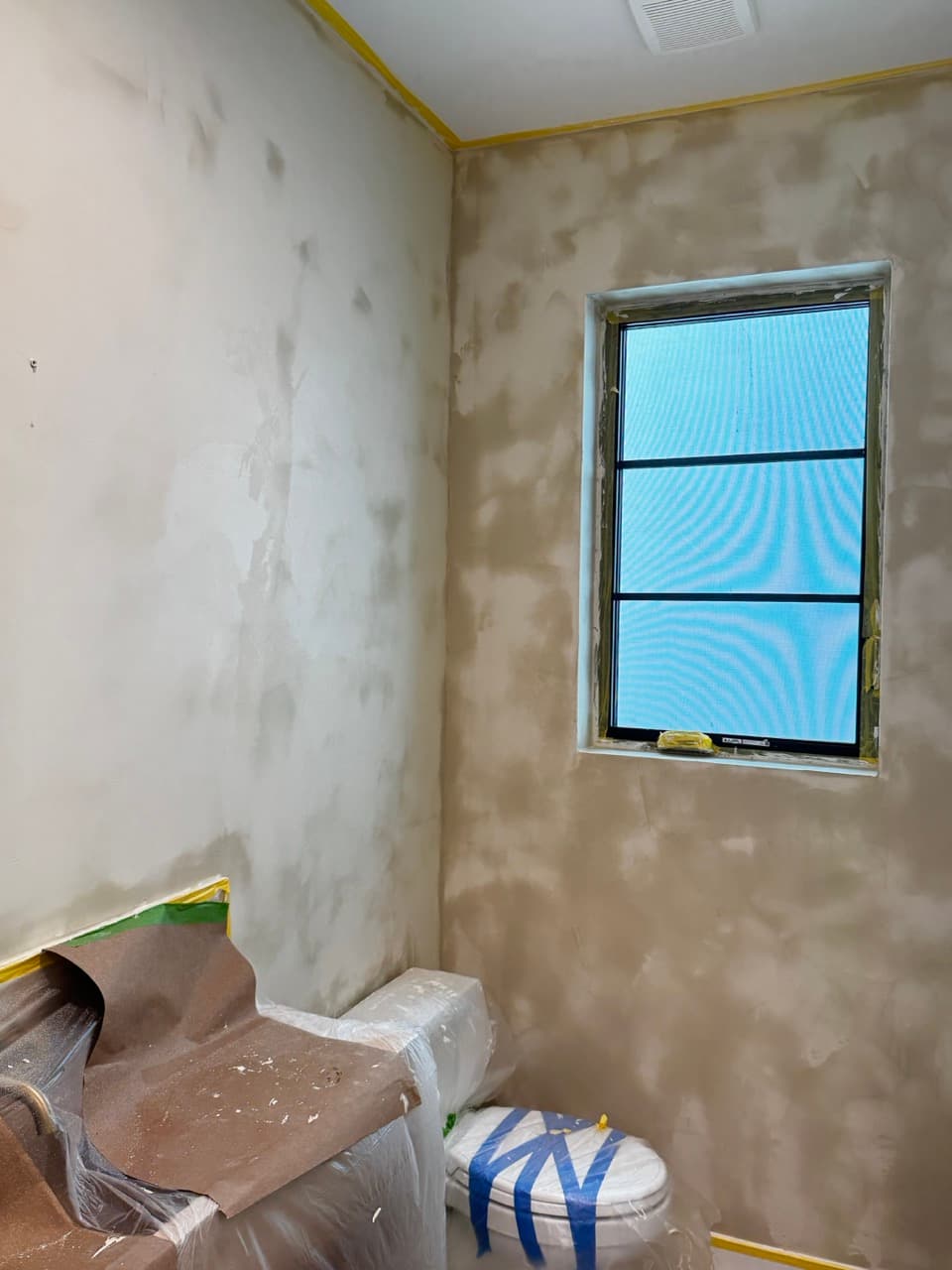 Powder room walls after the first coat of Marmorino Venetian plaster, window still masked.