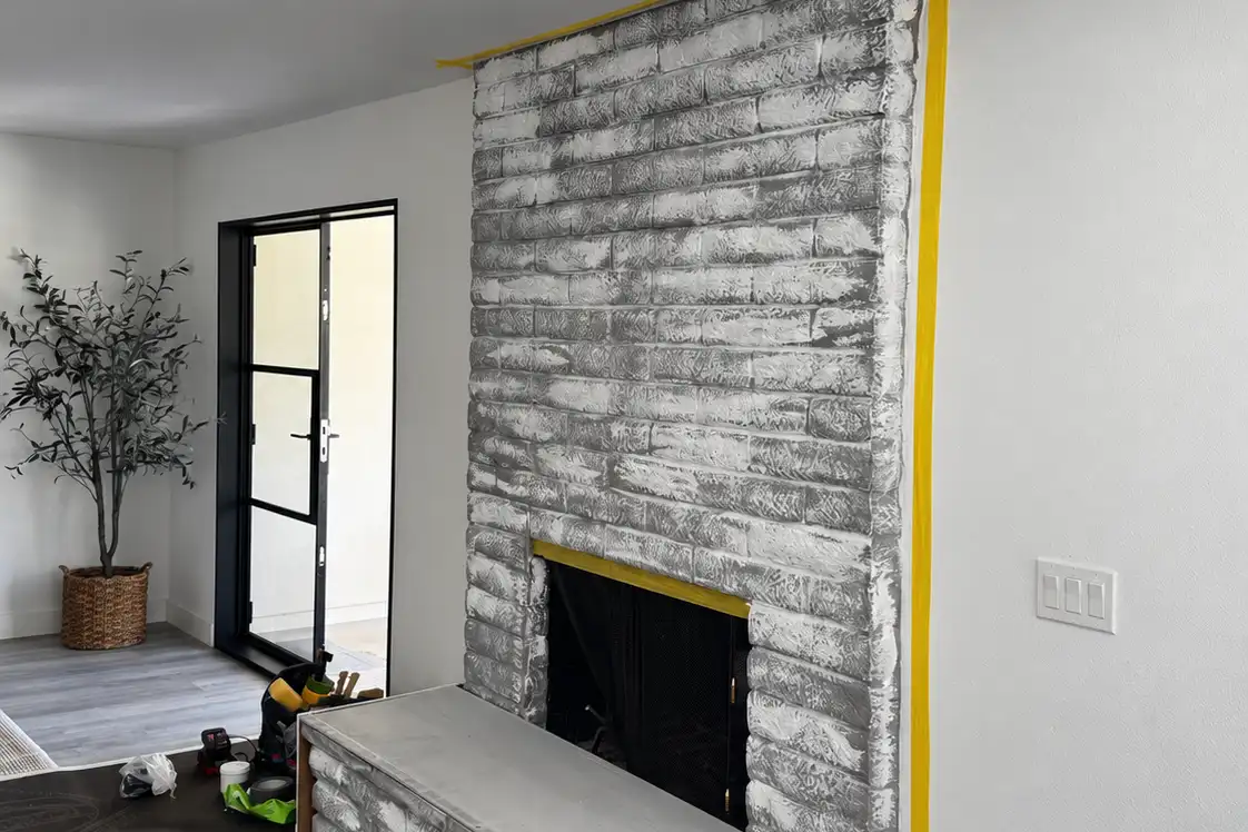 Existing painted brick masked off and the hearth reshaped during preparation, before the Marmorino Tintoretto finish.