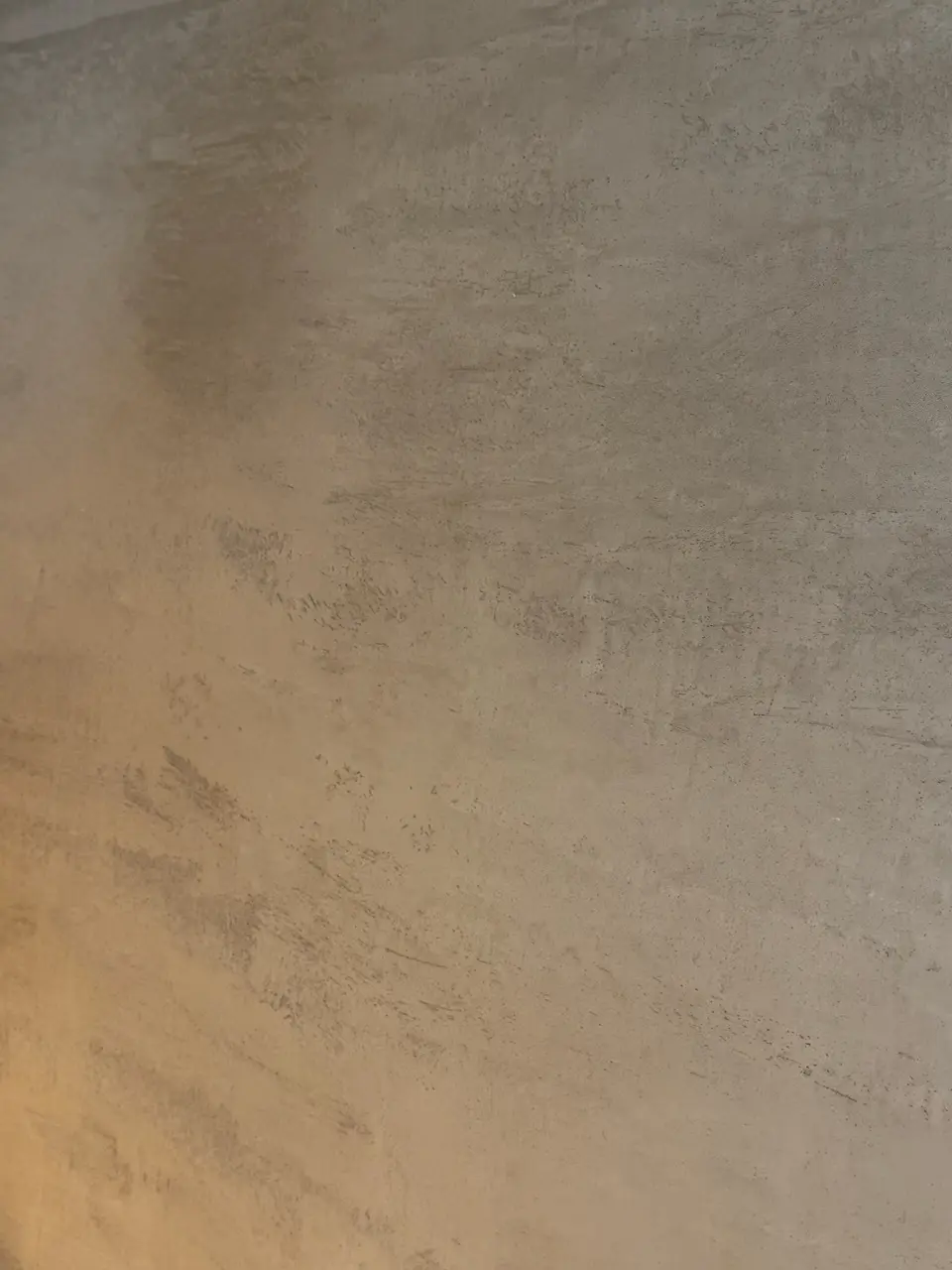 Close detail of the hand-applied Venetian plaster surface in a warm coffee travertine tone.