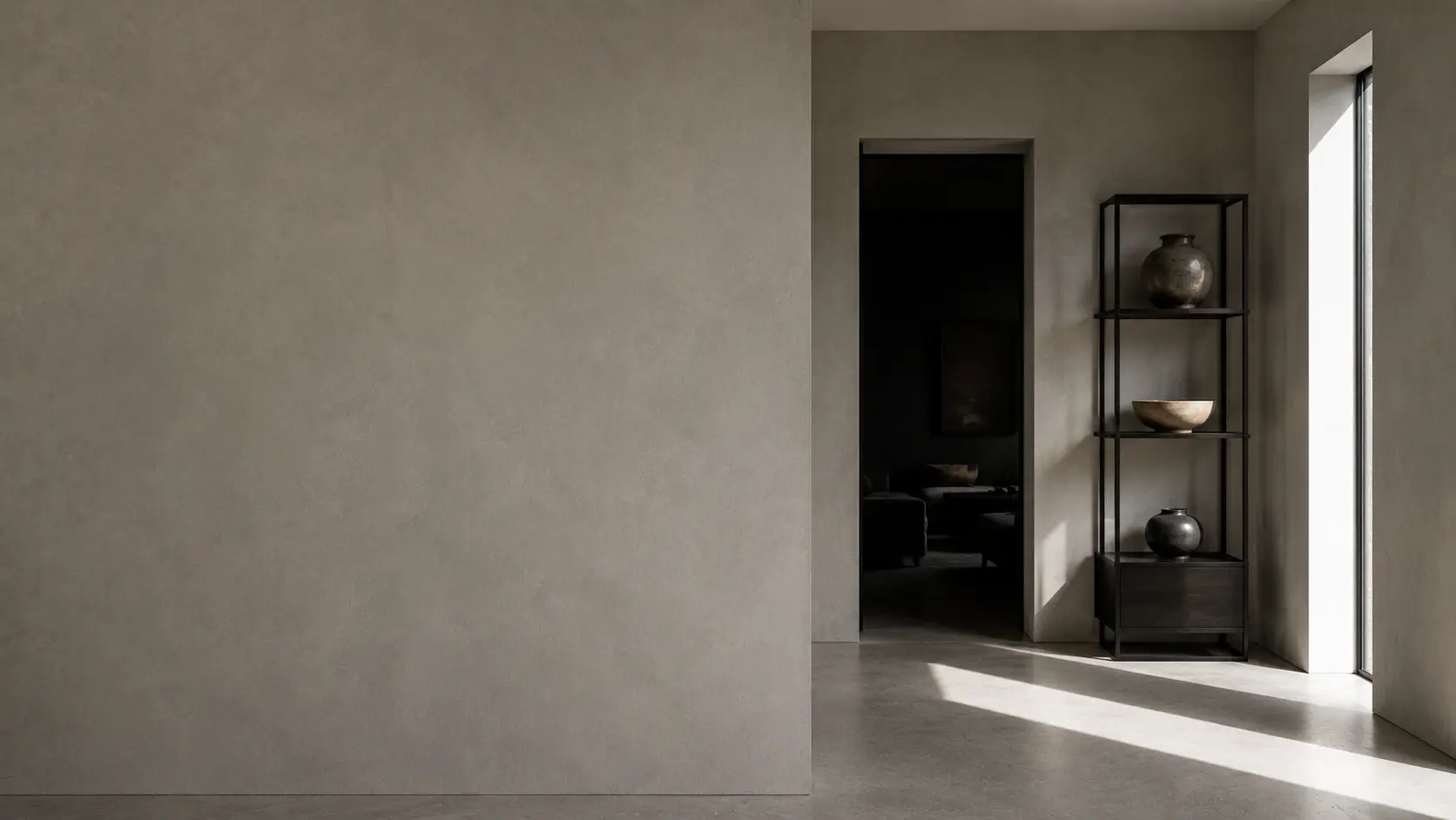 Minimalist interior with a seamless microcement wall, a dark doorway and a slim steel shelf