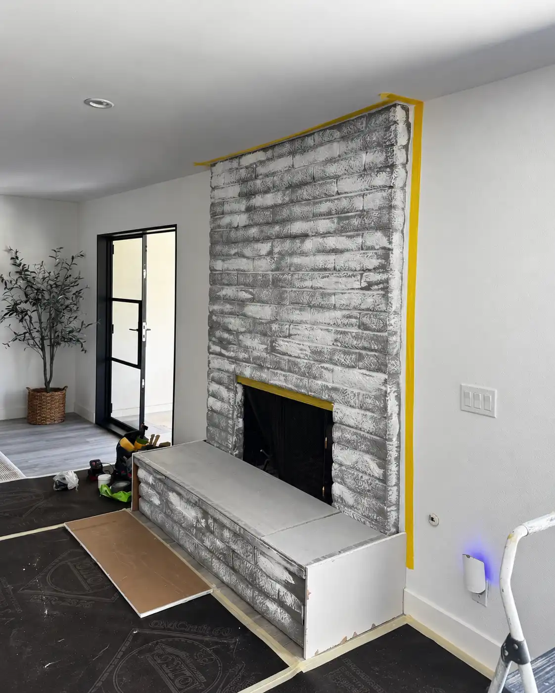 Existing painted brick masked off during early preparation for the fireplace renovation.