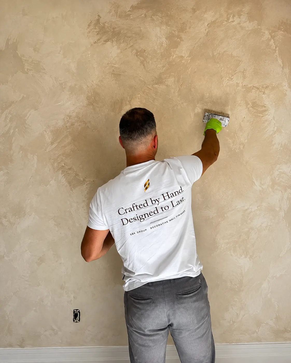 Specialist master hand-applying lime wash to an interior wall with a brush.