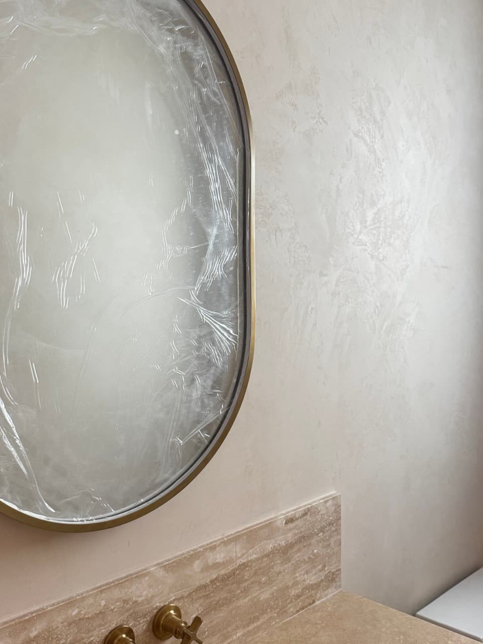 Marmorino Venetian plaster wall texture beside a powder room mirror and stone vanity.