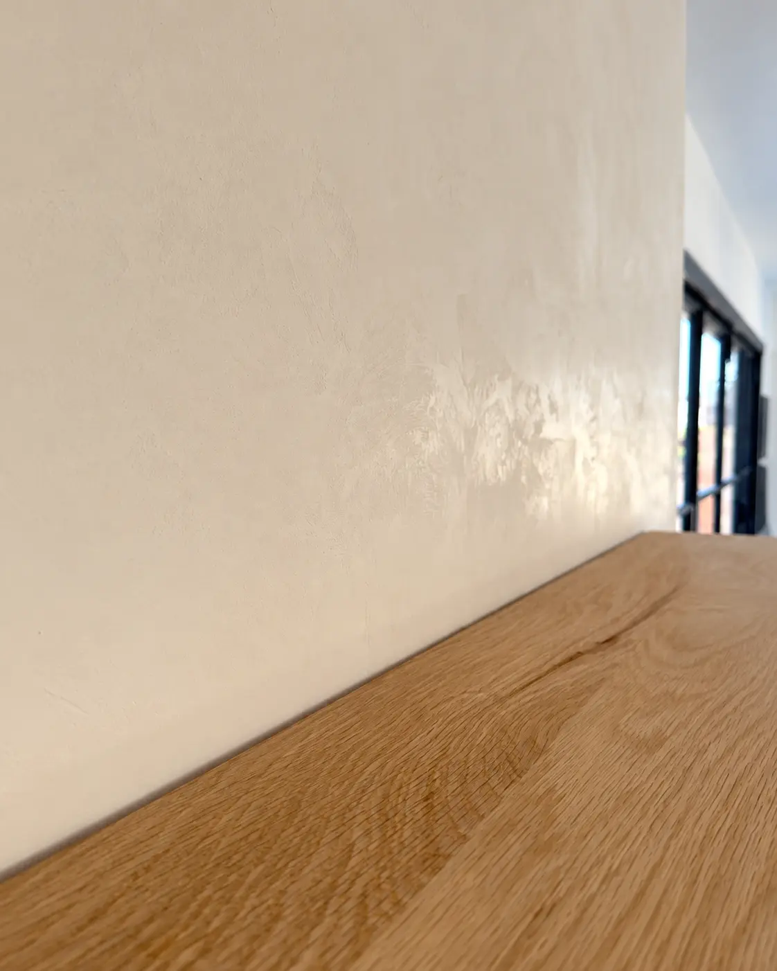 Close detail of the hand-applied Marmorino Tintoretto in Pure White beside the natural wood mantel.