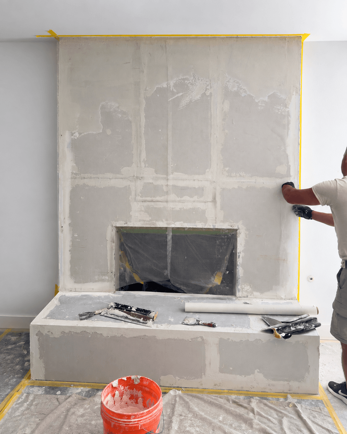 Framing and drywall build-out reshaping the fireplace form around the firebox before leveling.