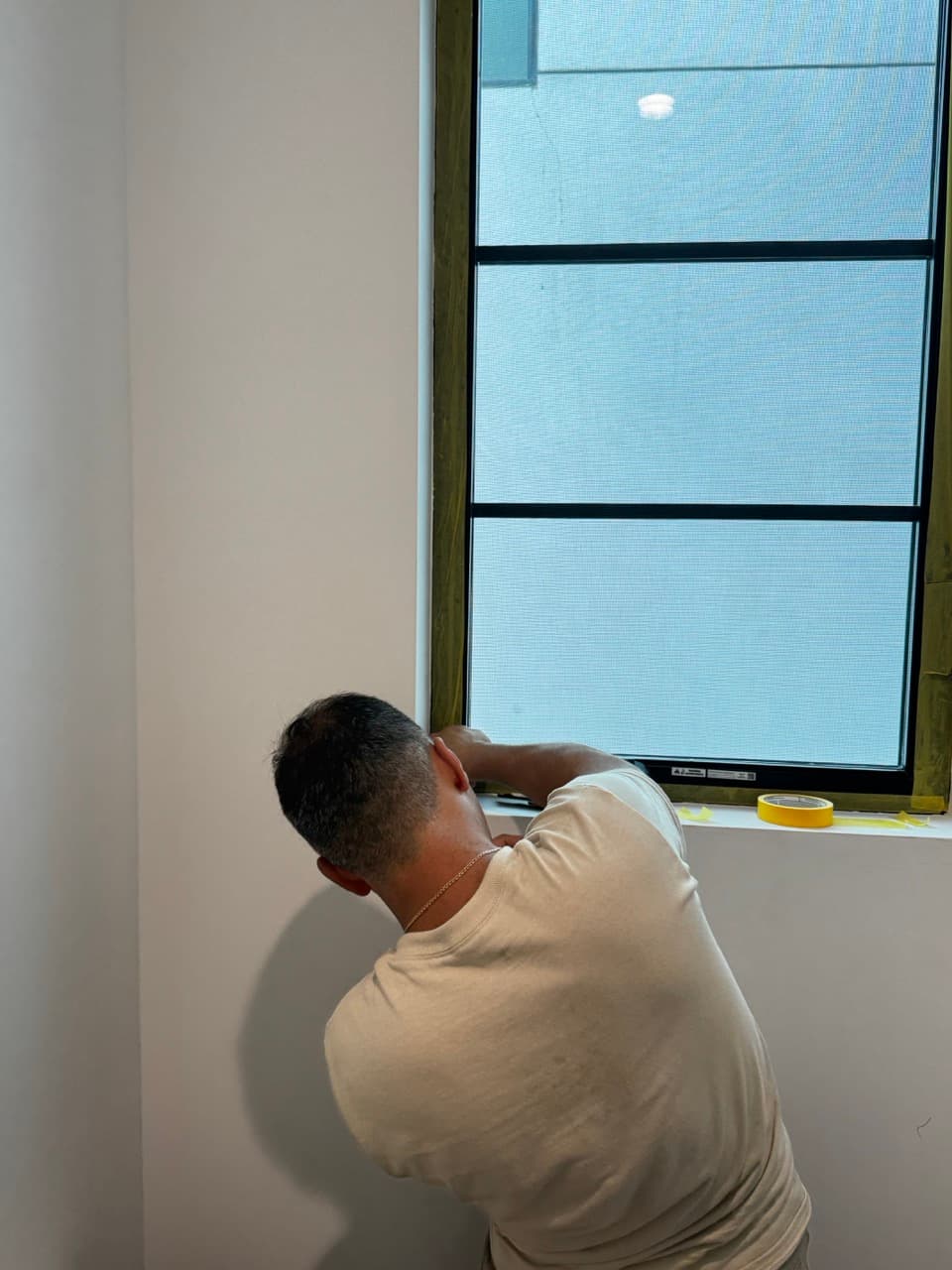 Masking a black framed window before Venetian plaster application in a powder room.