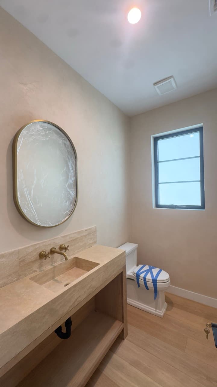 Finished peach Marmorino Venetian plaster walls around a black framed powder room window.