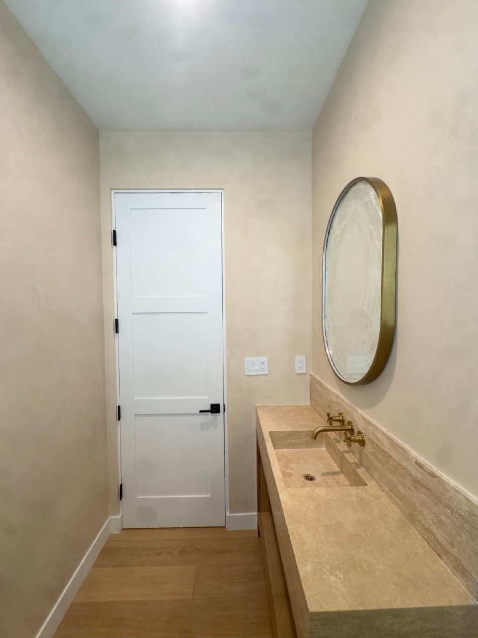Marmorino Venetian plaster walls beside the stone vanity and doorway in a Newport Beach powder room.